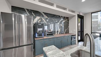 A modern kitchen with a stainless steel refrigerator and a marble countertop.